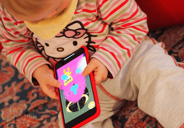 ein Kleinkind hält ein Smartphone